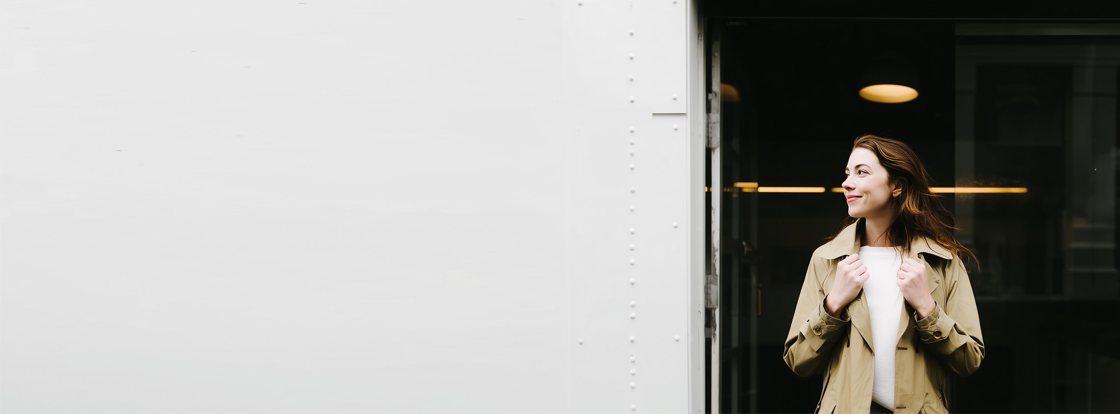 A woman stepping out of an office building into the daylight